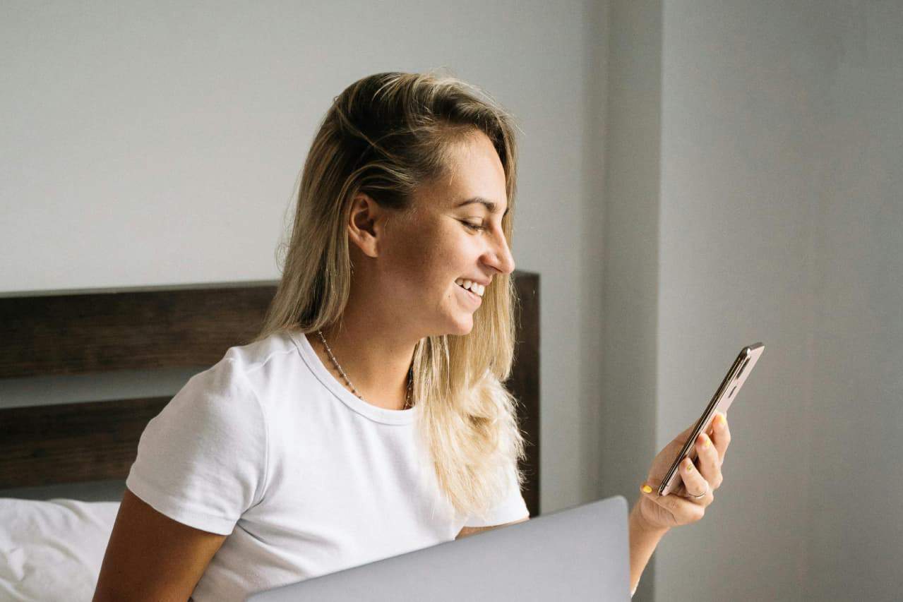 Donna sorridente che controlla lo stato di reso del suo ordine su uno smartphone