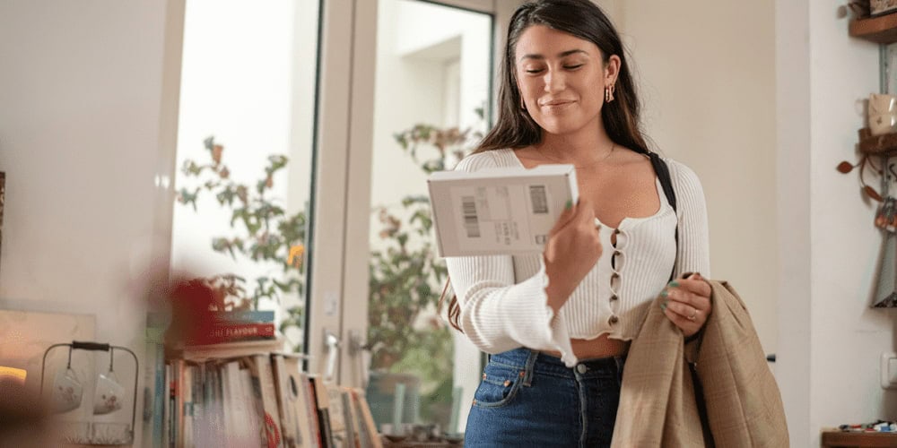 una donna riceve un pacco e sorride per avere ricevuto un’esperienza post vendita positiva